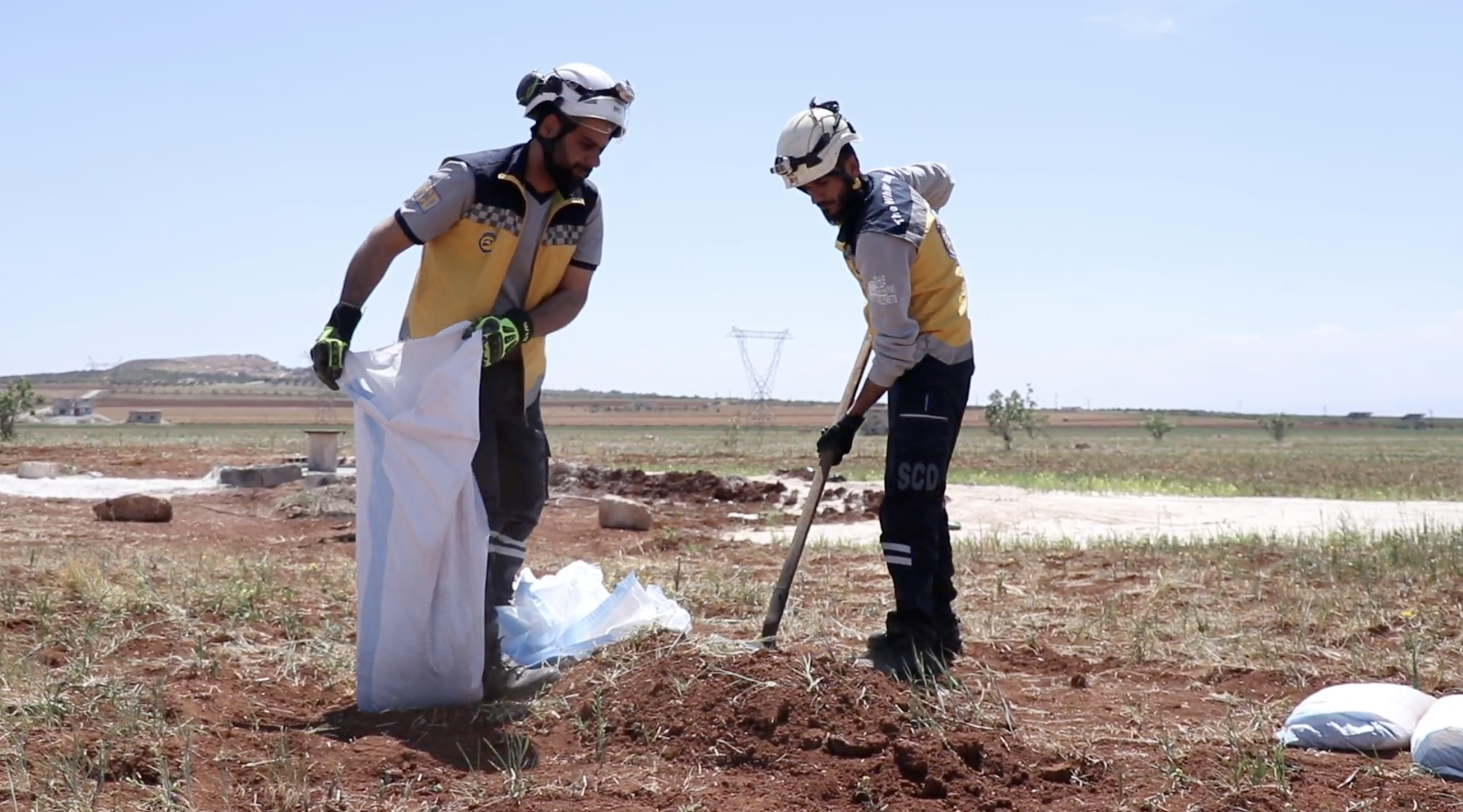 Two White Helmets personnel disposing of a cluster bomb near Khan Shaykhun, Syria, 27 April 2025.
