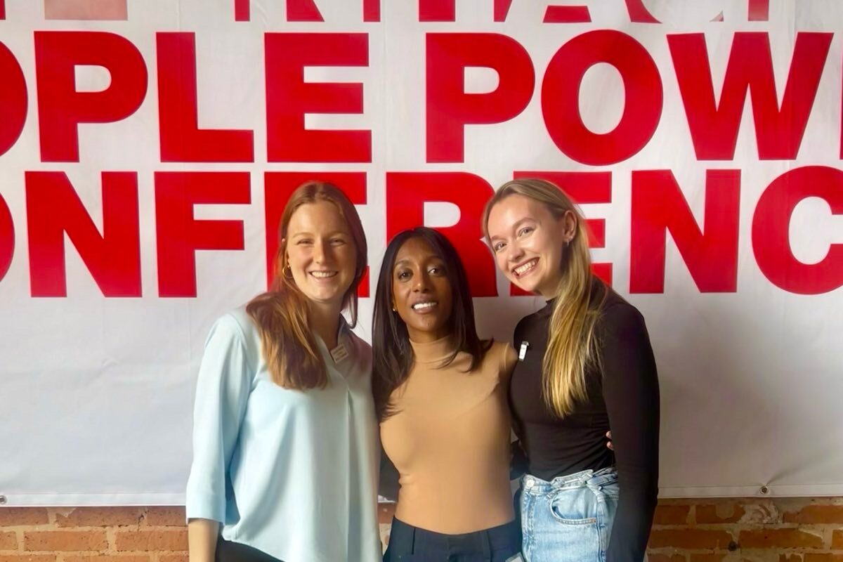 Leandra, Samah and Maike from the Right Livelihood team standing in front of the "Copenhagen People Power Conference" banner.